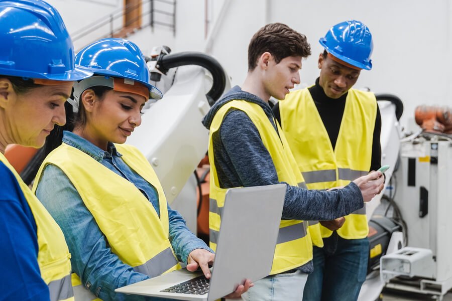 Logística de distribución practicas la logística - Equipo de trabajadores con cascos y chalecos de seguridad revisando información en dispositivos en el área industrial