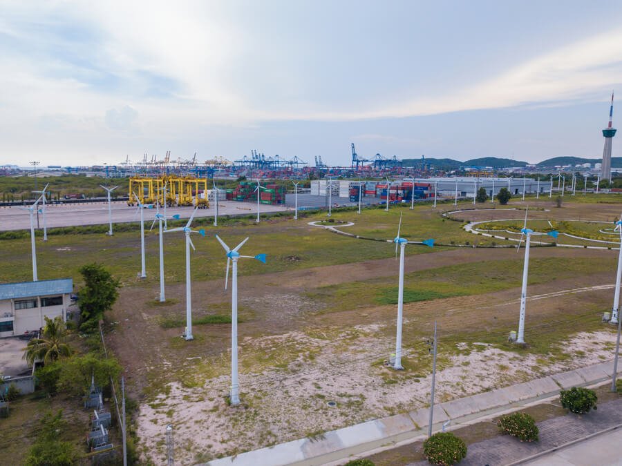 Logistica de distribucion recomendaciones - Vista aérea de parque eólico con aerogeneradores cerca de instalaciones portuarias y de carga